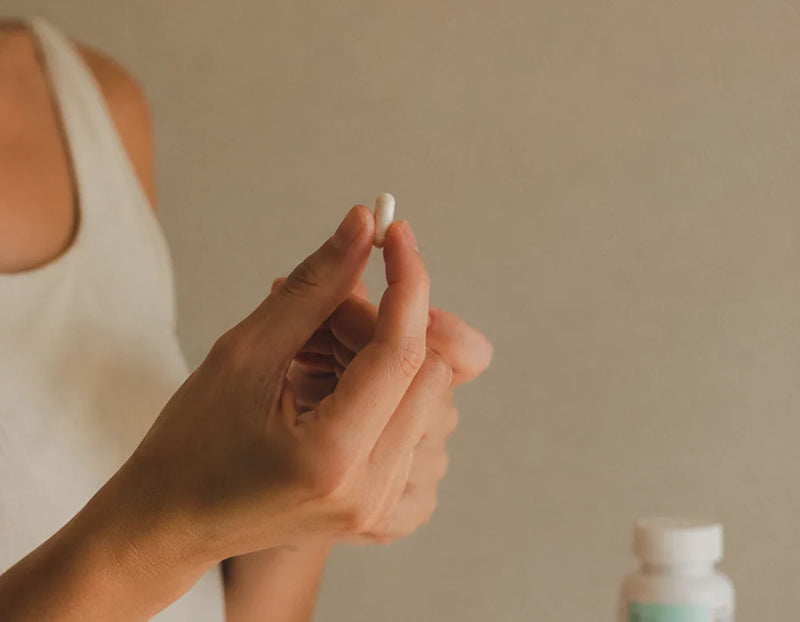 Cápsula de Bomba Nutricional ILEV en la mano, junto al desayuno